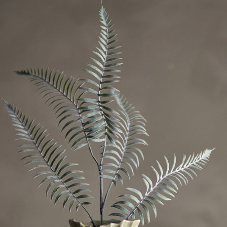 Sago Artificial Stem in green, a faux fern-like branch with arching fronds of narrow leaflets, shown upright in a vase against a plain brown background.