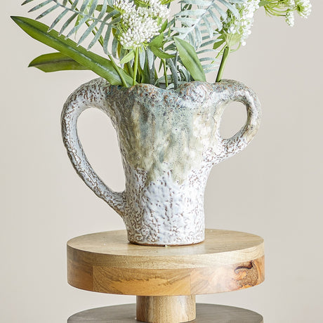 Ledger Speckled Stoneware Vase 21cm in White with wavy rim and two different-sized loop handles, holding greenery and white florals on a round wooden stand.