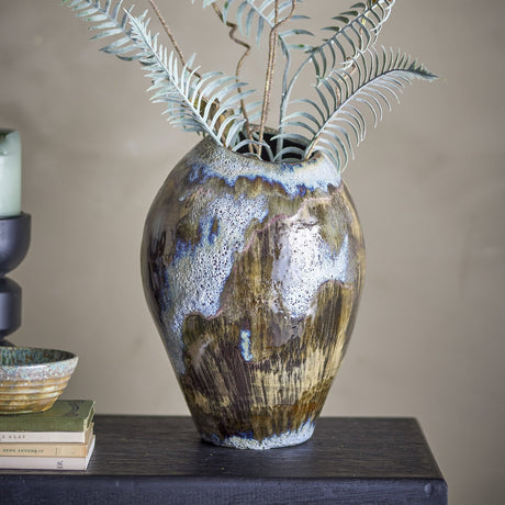 Senja Stoneware Vase 31.5cm in Brown, egg-shaped stoneware body with streaked brown glaze and speckled rim, shown on a dark console table styled with books and faux fern foliage.