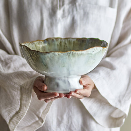 Joby Stoneware Bowl 24cm in Green, a footed ceramic bowl with wavy rim and green glaze fading to white at the base, shown held in two hands.