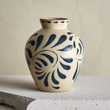 Heikki Stoneware Vase 24cm in cream, rounded ceramic body with bold blue leaf motifs and brown-dashed rim, shown on a stone ledge against a neutral background.