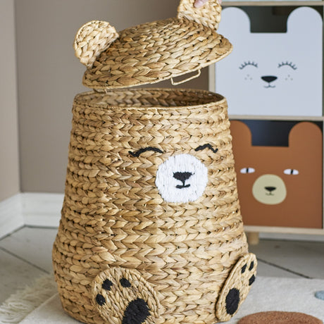 Timone Bear Water Hyacinth Basket with Lid, shaped like a sitting bear with rounded ears, stitched muzzle and eyes, and paw details, shown open in a nursery.