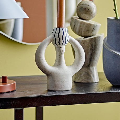Hatty Striped Stoneware Candle Holder in white, a looped figural design with a striped candle cup and simple face detail, shown on a shelf with a taper candle and decorative objects.