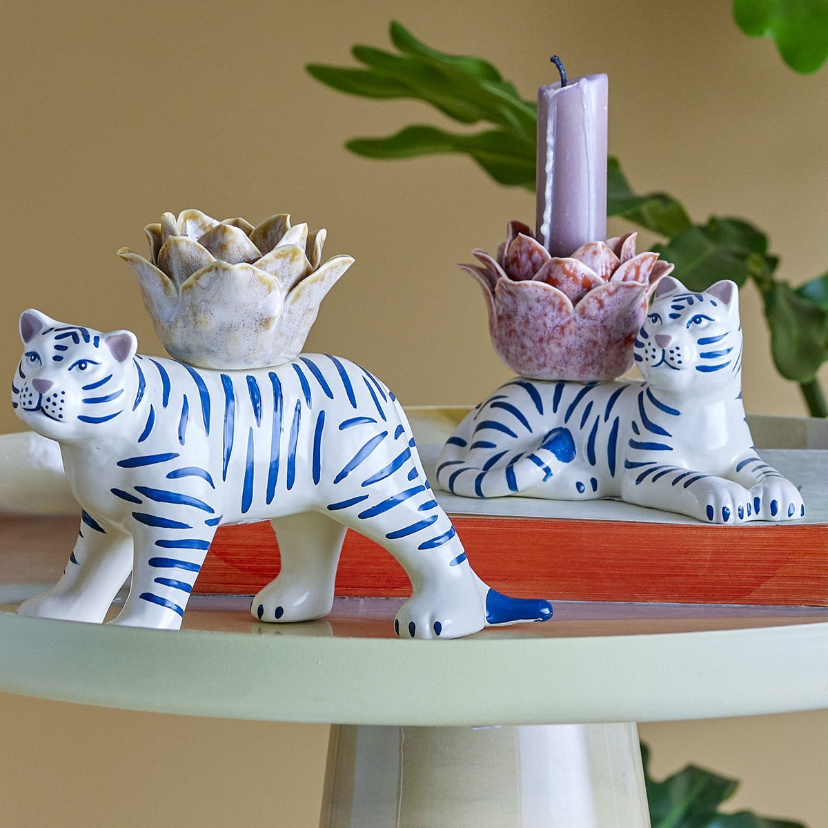 Rory Striped Stoneware Candle Holders set of 2: ceramic white tigers with blue stripes, each topped with a flower-shaped candle cup, one standing and one lying, shown on a tabletop.