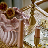 Petalia Stoneware Vase 17cm in pink, with a ribbed glossy body and ruffled speckled collar, shown on a tabletop with candles and dried flowers.