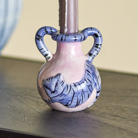 Ryker stoneware candle holder with a two-handled vase shape, pink glaze and a hand-painted blue striped cat curling around the round body.