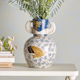 Hezha Floral Stoneware Vase 23.5cm in blue and white, with a round body featuring a painted bird and floral pattern, bird-head handles, and a blue foliage-banded neck, holding greenery on a shelf.