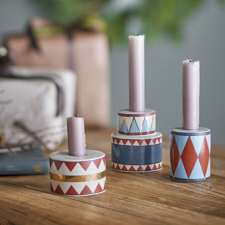 Bitja Geometric Christmas Candle Holders, set of three multicoloured stoneware pieces with zigzag and diamond patterns, holding pink taper candles on a wooden table.