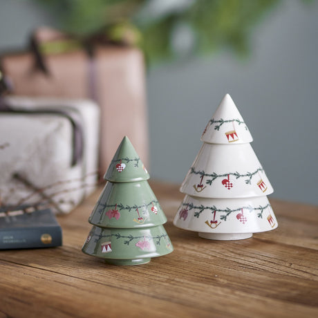 Yule Stoneware Christmas Decorations Set of 2 - tiered ceramic trees in green and white with painted fir garlands and ornament details, displayed on a wooden table with gift boxes.