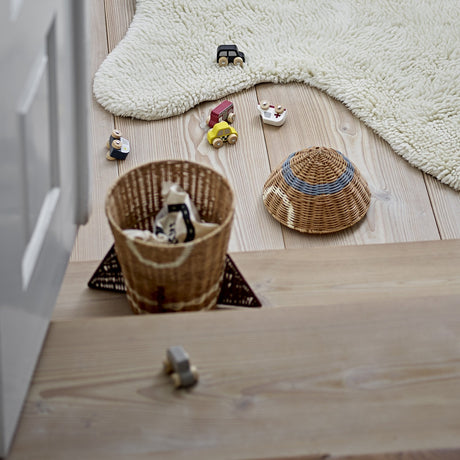 Space Rocket rattan storage basket with lid removed, round woven body and triangular fin base in natural tone, shown on a wooden floor beside toys and a rattan hat.