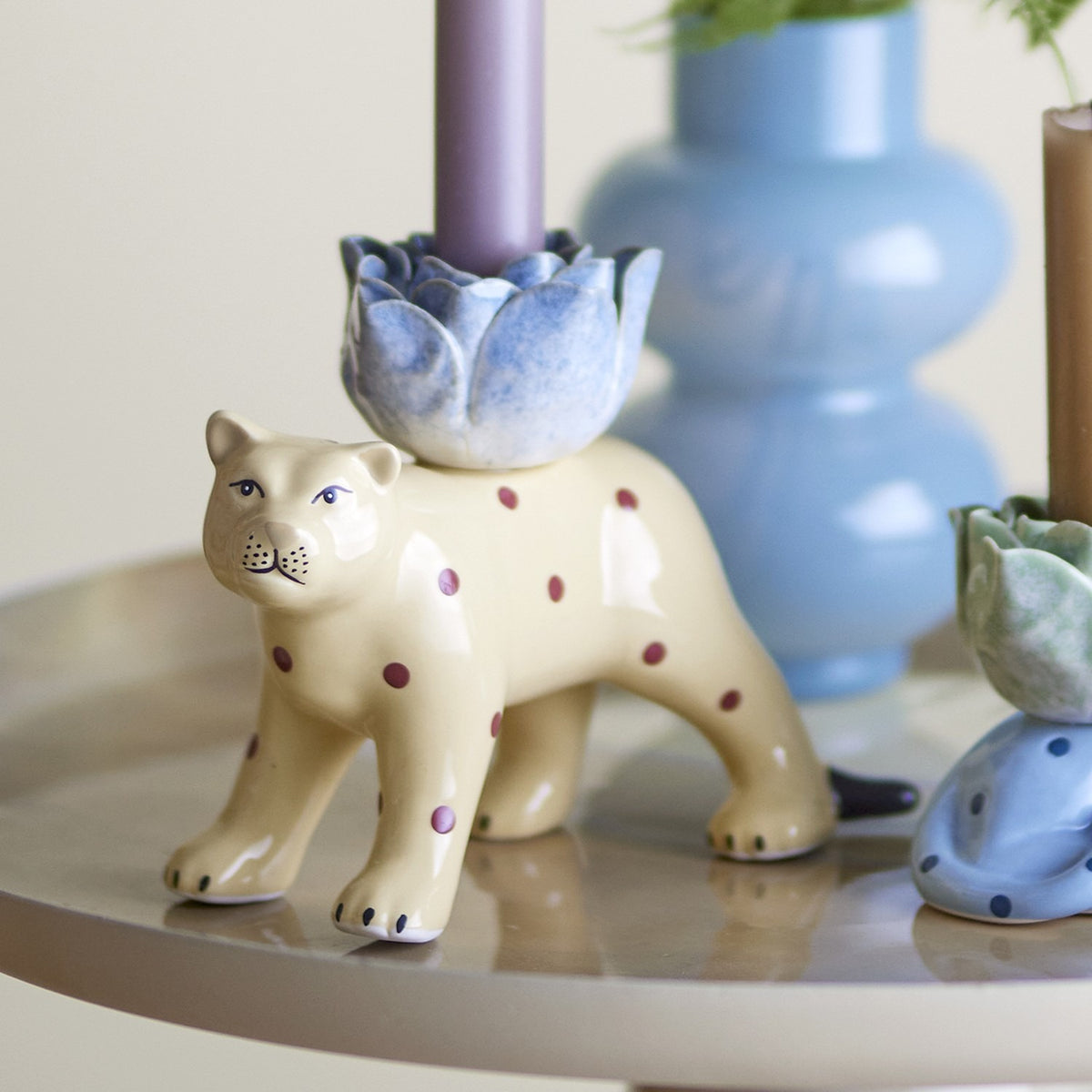 Rory Cat Stoneware Candle Holder, cream glazed standing cat figure with red polka dots carrying a petal-shaped cup for a taper candle, shown among decorative vases.