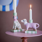 Doglie Striped Stoneware Candle Holders Set of 2 in pink, dog-shaped ceramic candle holders on checkered bases, shown with white candles on a pink side table.