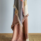 Arni Throw in Multi draped vertically, showing a woven curved colour-block design in grey, pink, tan and cream with a thick mixed-yarn fringe, against a plain light background.