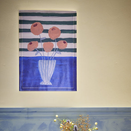 Florinda Striped Wooden Framed Print in Multi, showing a painterly bouquet of peach flowers in a striped vase against green and white stripes with a blue tabletop band.