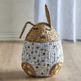 Villja rabbit-shaped kids storage basket in water hyacinth, with a sleeping-face lid, two braided ears, and a dotted multicoloured egg-shaped body with paw feet.