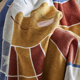 Sun Cotton Throw in multicoloured woven cotton blend, close-up of a smiling sun face with closed eyes and rounded cheeks, draped in folds with star and grid patterns visible.