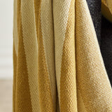 Frello Striped Cotton Throw in yellow, draped in folds showing alternating deep and pale yellow woven stripes with a textured cotton blend finish.