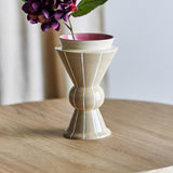 Trilla Striped Ceramic Vase 26.5cm in beige with an hourglass-and-bulb silhouette, vertical white stripes, and a pink-glazed rim, shown with flowers on a wooden table.