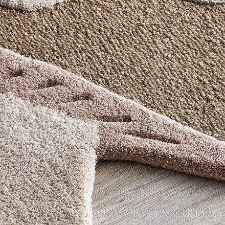 Close-up of the Mushroom Wool Rug 90x85cm in brown, showing the looped cap texture, raised lighter spots, carved gill band, and rounded tufted stem edge on a wooden floor.