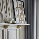 Bie Geometric Cotton Wall Decor in beige, framed textile art with woven jute bands forming a grid over rounded and square outlines, shown on a mantel shelf.