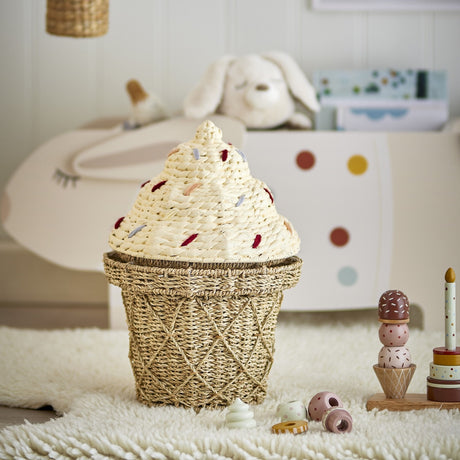 Cillie Seagrass Basket with Lid 41cm in natural, shaped like an ice cream cone with a lattice-woven base and domed, sprinkle-stitched lid, shown in a nursery setting.