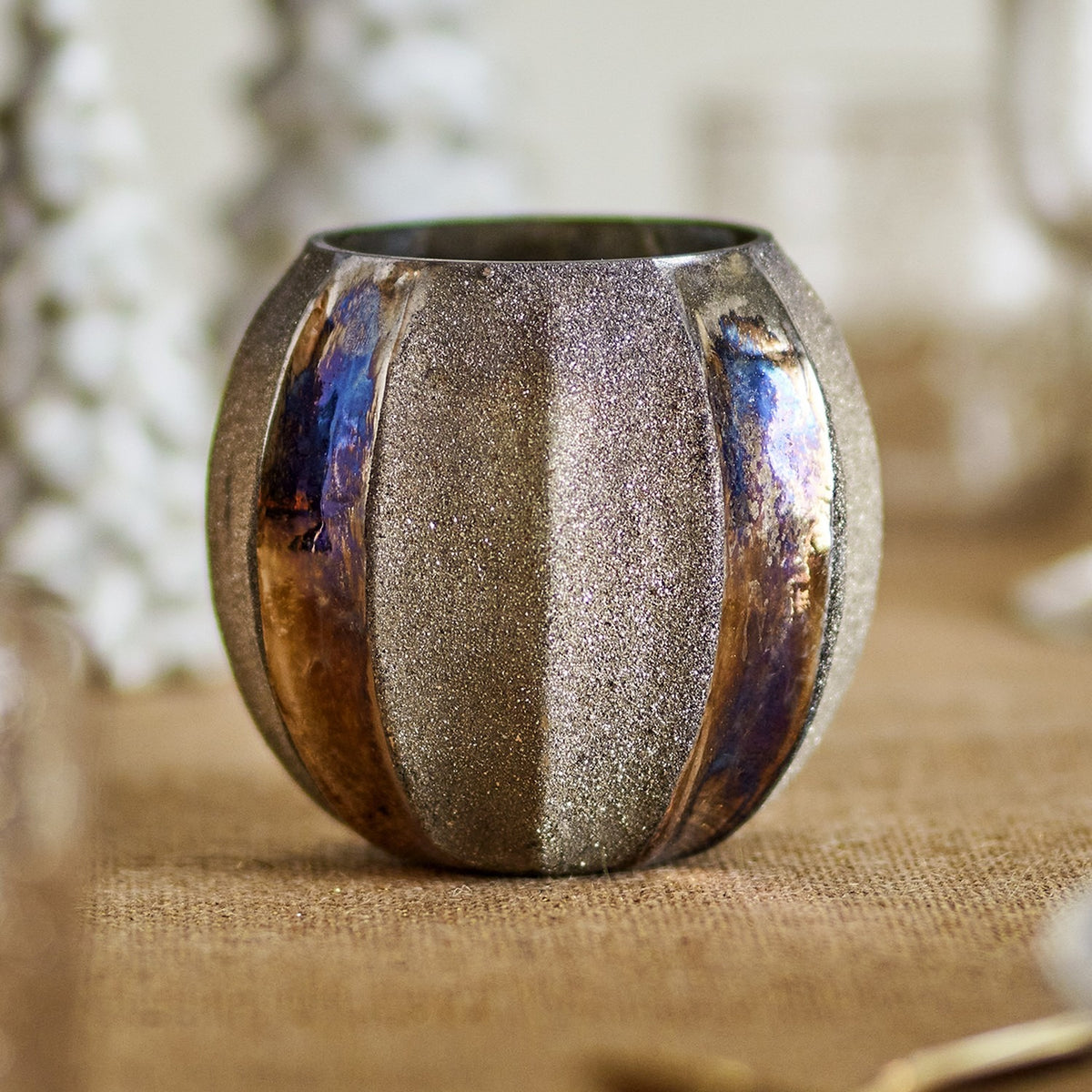 Felecia Striped Glass Christmas Tealight Holder in gold, round recycled glass design with alternating textured and iridescent oxidised vertical panels, shown on a table setting.