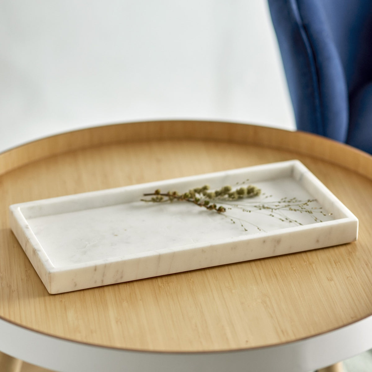 Majsa Marble Tray 38x18cm in white, a rectangular raised-rim tray with soft grey veining, shown on a wooden side table with a sprig of greenery.