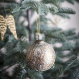 Nany Glass Christmas Bauble in bronze, a round 10cm ornament with crackled, crazed glass texture and a metal cap and loop, hanging from a Christmas tree branch.