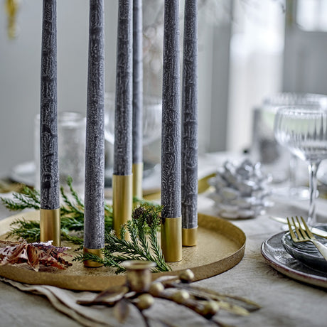 Maxime Iron Christmas Candle Holders Set of 7 in gold, round textured tray holding slim gold tube holders with grey taper candles and greenery, styled on a table.