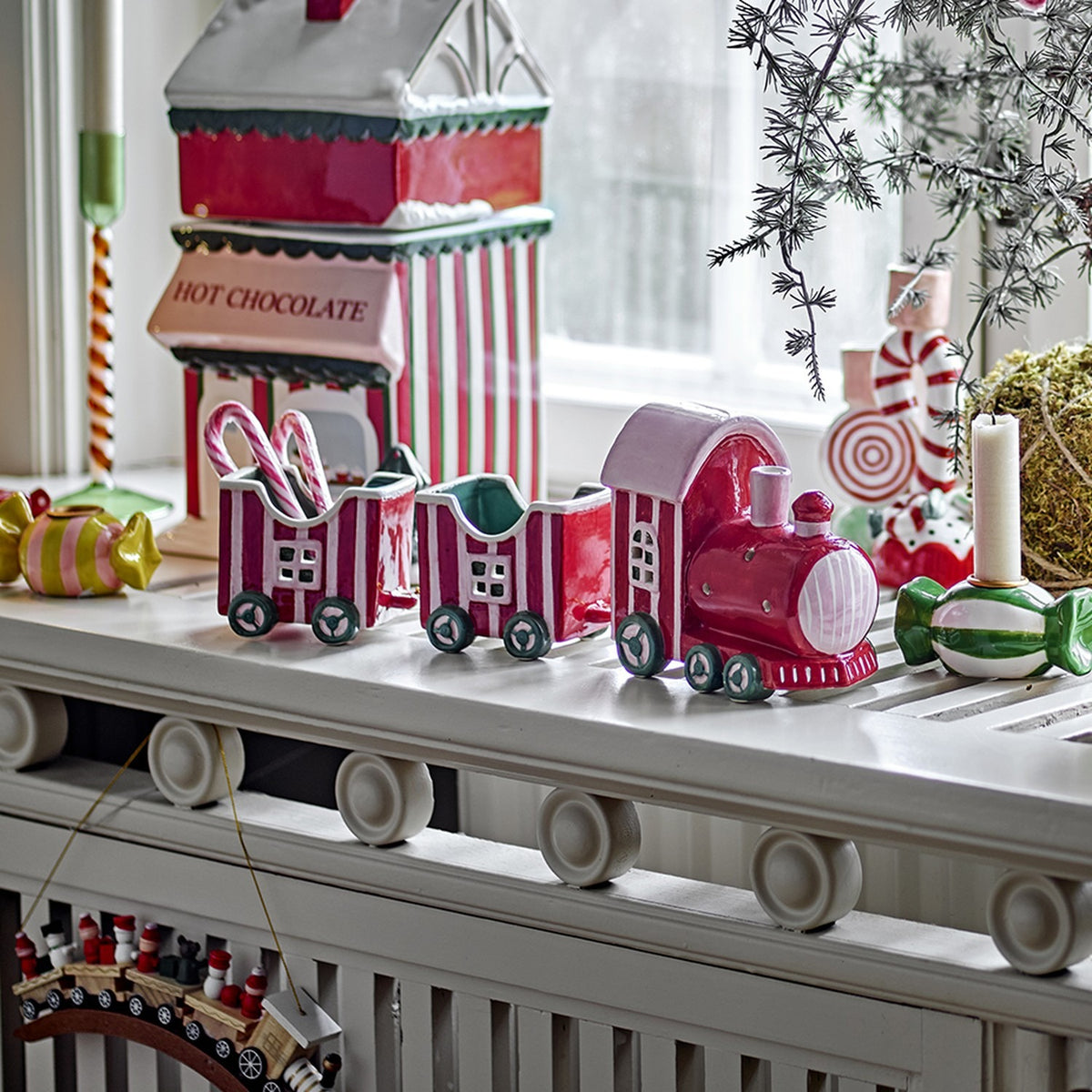 Gloria Striped Ceramic Christmas Decoration in red, a three-piece ceramic train with chimneyed locomotive and two open wagons, shown on a mantel with festive decor.