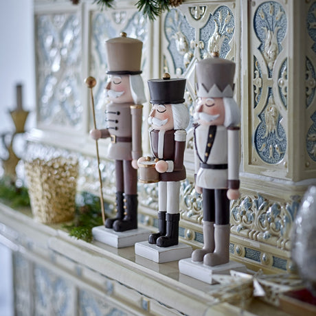 Darryl Resin Christmas Decorations Set of 3 in Brown, nutcracker-style figures with tall hats, painted moustaches and buttoned jackets, displayed on a mantel in varying heights.