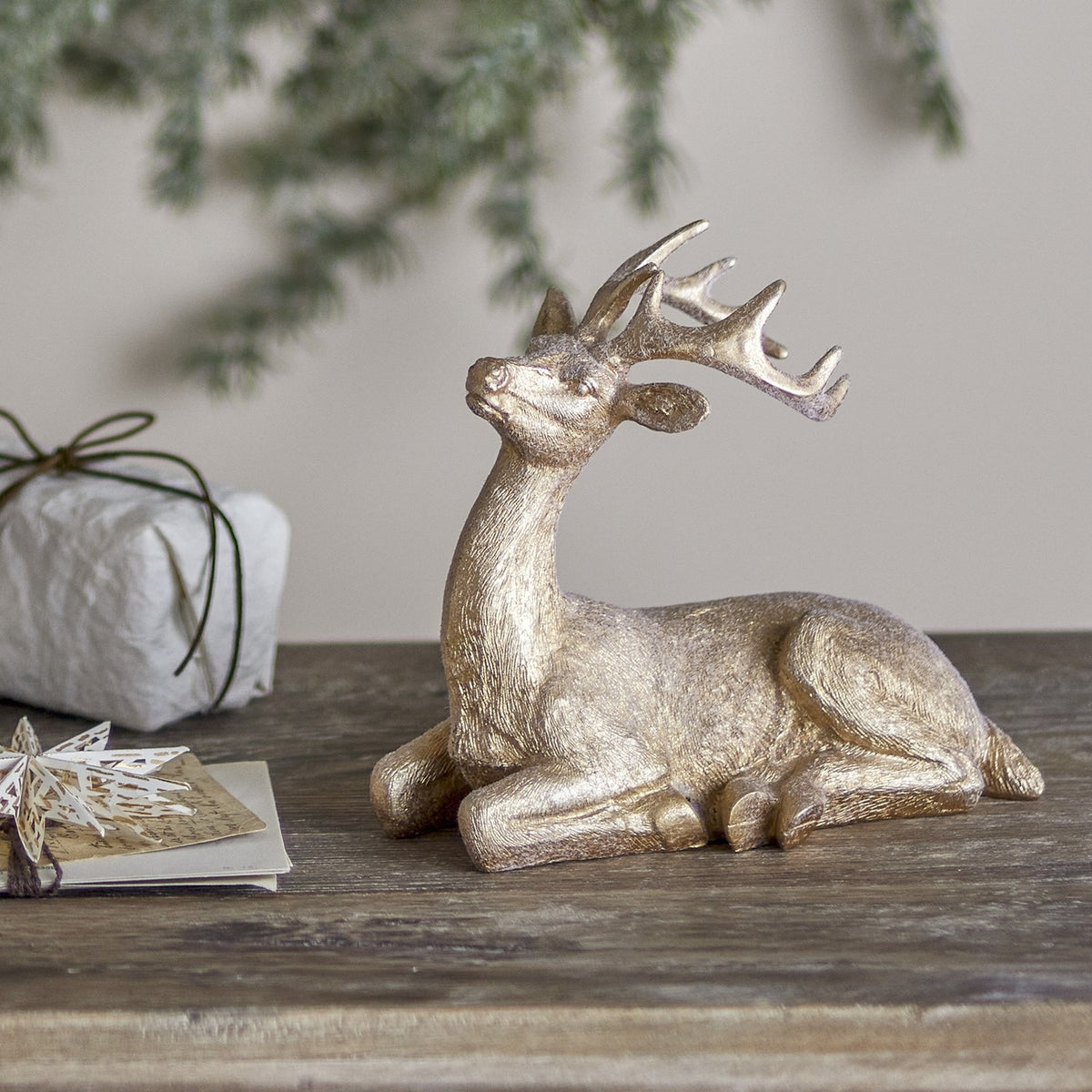 Pranzer gold resin Christmas deer decoration, 20cm, lying with antlers raised, textured finish, displayed on a wooden table with festive décor.