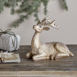 Pranzer gold resin Christmas deer decoration, 20cm, lying with antlers raised, textured finish, displayed on a wooden table with festive décor.