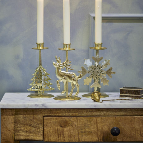 Sauda gold iron Christmas candle holders set of 3, featuring tree, stag, and snowflake motifs with taper candles, styled on a marble-top wooden console.
