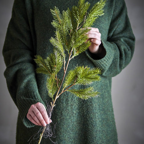 Pine Artificial Christmas Stem, 56cm, green faux pine branch with fine needles held in hand against a dark green sweater.