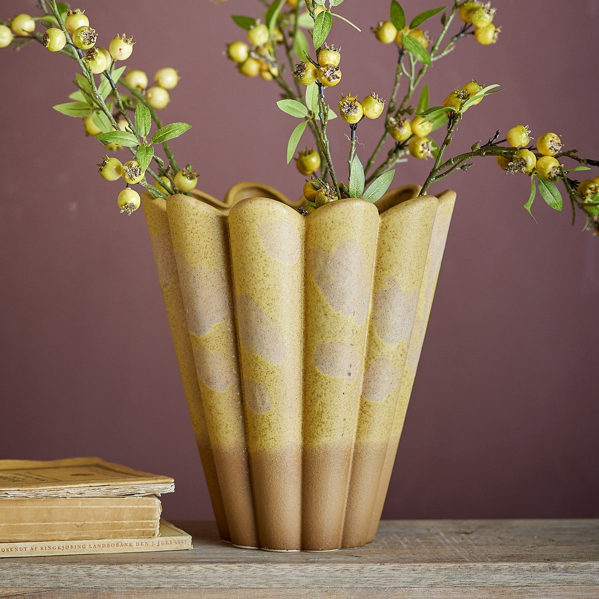 Penn Speckled Stoneware Vase 29cm in yellow with fluted, scalloped rim and speckled glaze over an earthy base, holding berry branches on a wooden surface against a mauve wall.