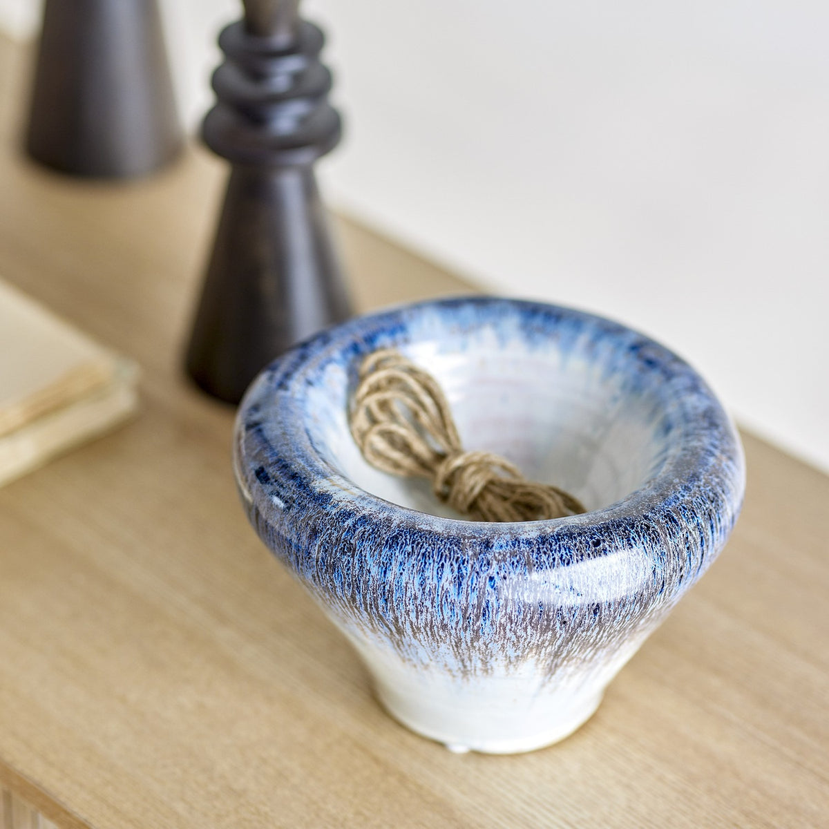 Finna Stoneware Bowl 17cm in Blue with a thick rolled rim and tapered white base, shown on a wooden surface with twine inside beside dark candlestick holders.