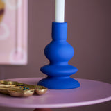 Thorne Stoneware Candle Holder 16cm in Blue, a matt ceramic holder with stacked curves holding a white taper candle on a pink side table.