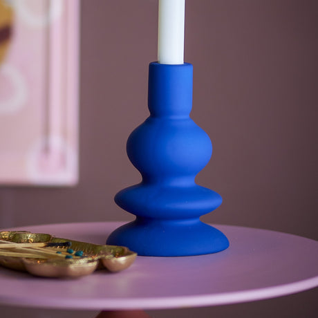 Thorne Stoneware Candle Holder 16cm in Blue, a matt ceramic holder with stacked curves holding a white taper candle on a pink side table.