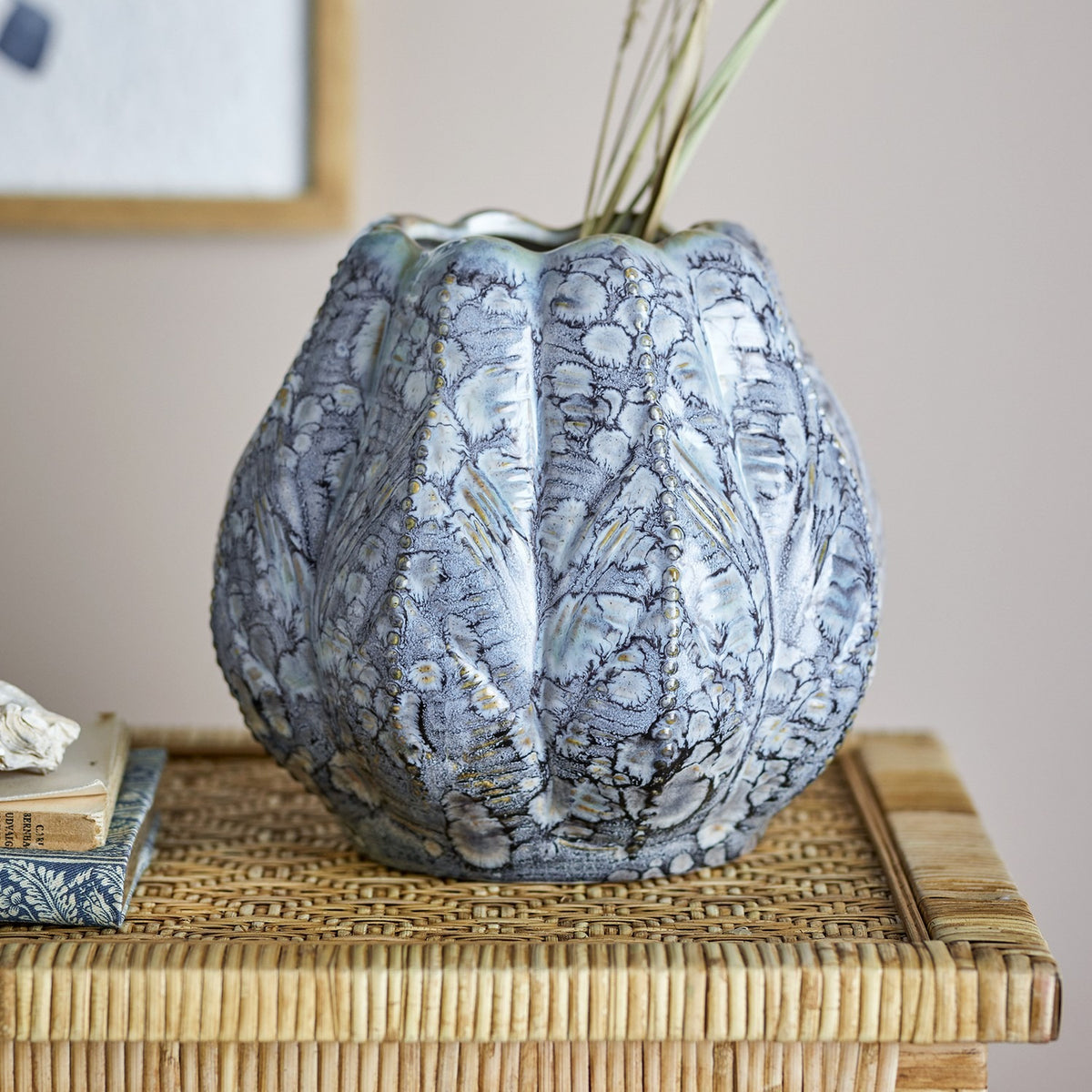 Hetty Stoneware Vase 19.5cm in blue, a rounded ribbed vase with beaded edges, scalloped rim, and textured glaze, shown on a woven side table with books.