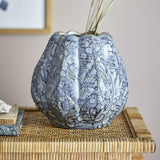 Hetty Stoneware Vase 19.5cm in blue, a rounded ribbed vase with beaded edges, scalloped rim, and textured glaze, shown on a woven side table with books.