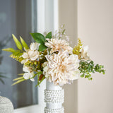 Cream Glow artificial bouquet with dahlia blooms, hydrangea florets, fern fronds and eucalyptus sprigs in a white beaded vase, set in a living room.