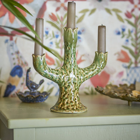 Cyrill Stoneware Candle Holder in green, a branching cactus-shaped design with three scalloped cups holding taper candles, shown on a table with decorative accents.
