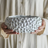 Lowen Stoneware Bowl 24cm in white, held in two hands, showing its wide, low shape with textured fan-motif relief and a pearly glazed finish.