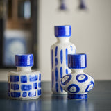 Romane Stoneware Vases Set of 3 in blue: a tall slim vase with vertical strokes, a squat cylinder with checked blocks, and a bulbous vase with bold circles, on a dark surface.