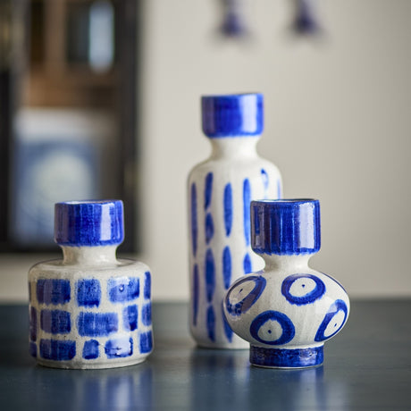 Romane Stoneware Vases Set of 3 in blue: a tall slim vase with vertical strokes, a squat cylinder with checked blocks, and a bulbous vase with bold circles, on a dark surface.