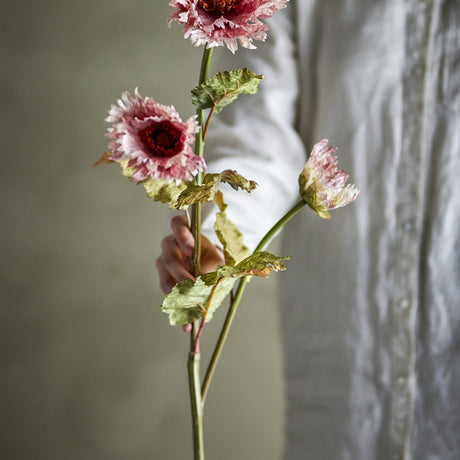 Chrysanthemum Artificial Stem 96cm in pink, held by hand, showing two open frilled blooms and one closed bud with veined leaves along a long bare stem.