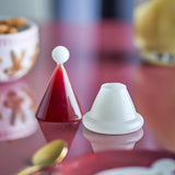 Patrice Glass Christmas Toothpick Holder in red, shaped like a Santa hat with a white ball-tip cone lid and white cup base, shown on a reflective red table.