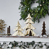 Kaiam Iron Christmas Decorations Set of 2 in gold, two tiered fir-tree ornaments with dimpled texture, displayed on a mantel with candles and a wreath.