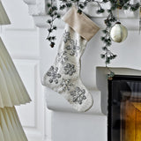 Ahsan Snowflake Cotton Christmas Decoration in beige, a woven fabric stocking with a folded cuff and beaded snowflake details, hanging from a mantelpiece.